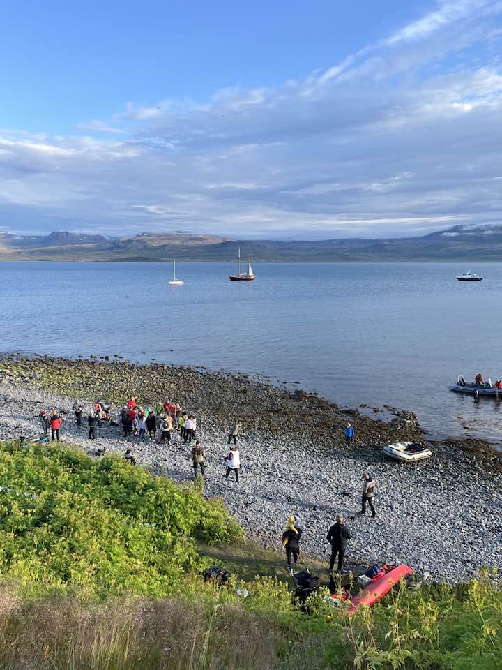 Gestir í fjörunni í Kvíum. Úti á firðinum eru nokkrar skútur og í fjörunni eru gúmmíbátar og kajak.