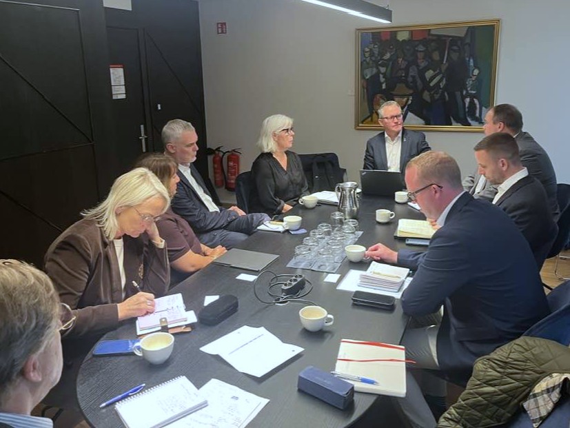 Fólk við fundarborð. Níu manns í heildina. 