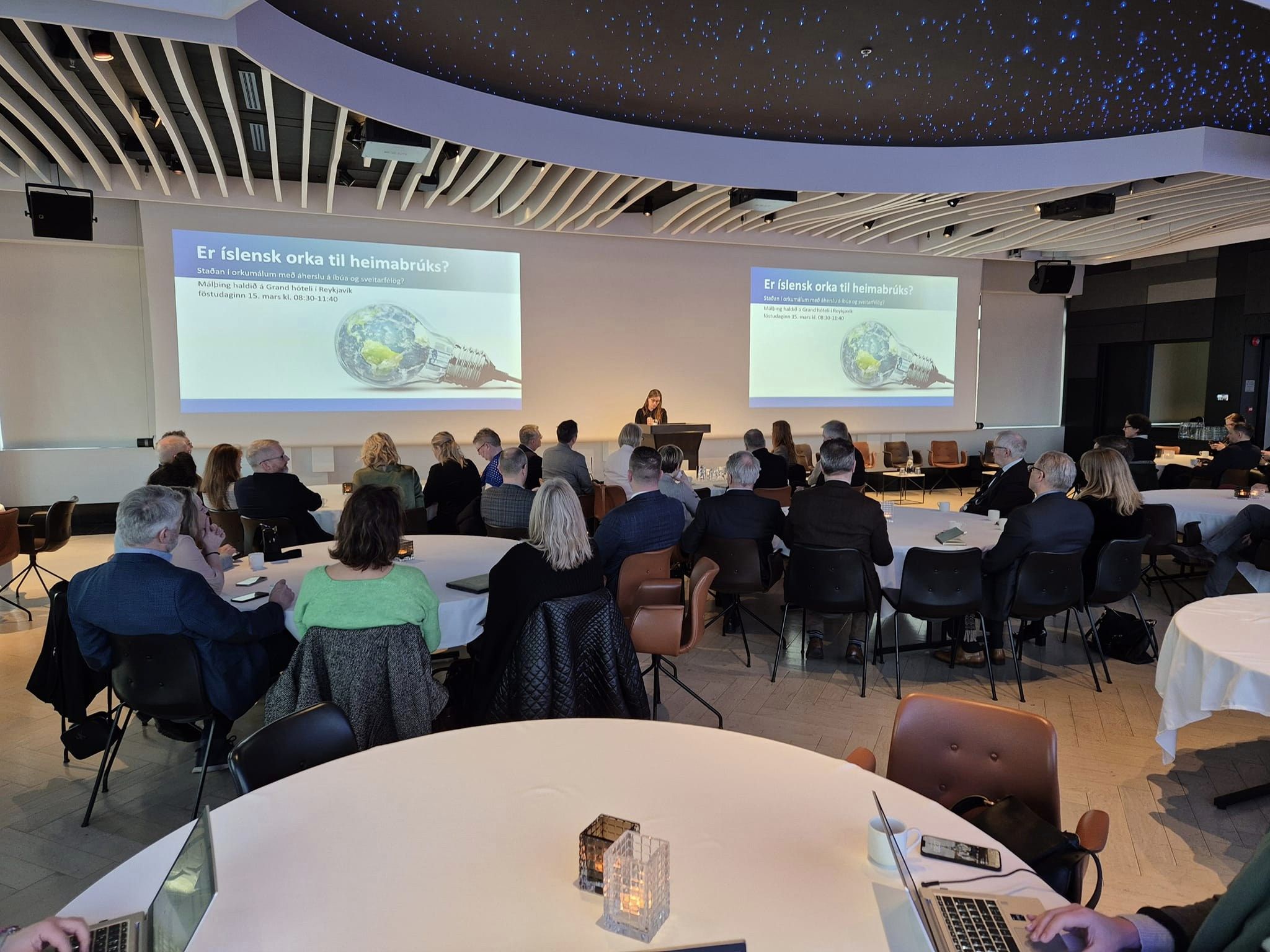 Málþing á vegum sveitarfélaga á köldum svæðum. Katrín Jakobsdóttir er í pontu. Fyrir aftan hana er myndum varpað á tjald. Í fundarsal situr fólk við hringborð.