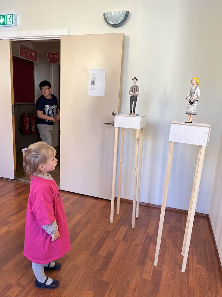 Jódís Magga stendur og virðir fyrir sér lítinn skúlptúr af Vigdísi Finnbogadóttur.