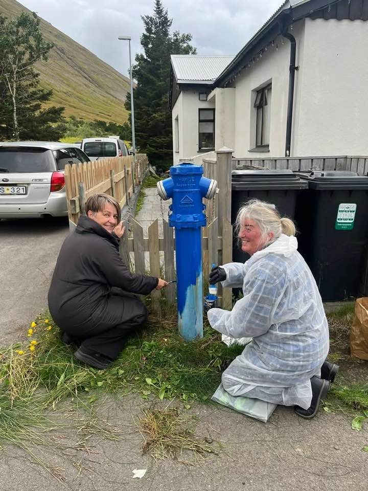 Tvær konur mála brunahana bláan.