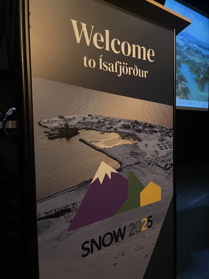 Kynningargardína á SNOW-ráðstefnunni. Á henni er mynd af Flateyri sem er tekin skömmu eftir flóðið 2020, og texti sem segir: Welcome to Ísafjörður.