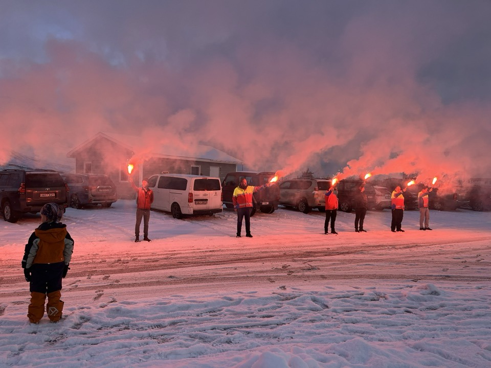 Björgunarsveitarfólk með blys við Hafnarstræti á Flateyri.