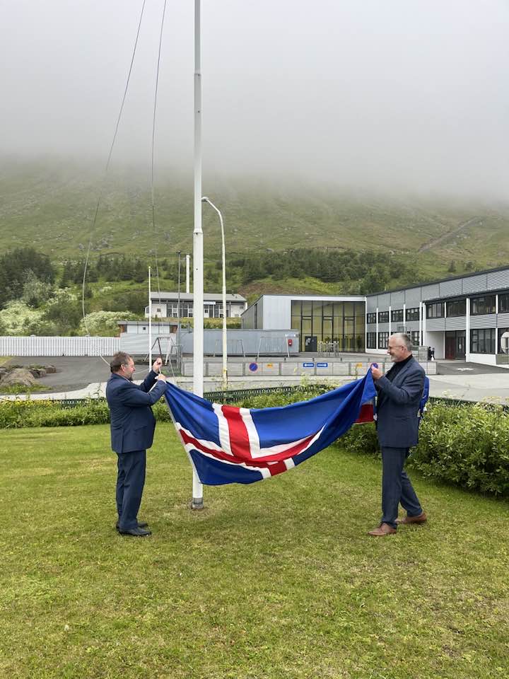 Tveir menn undirbúa flöggun íslenska fánans við kirkjuna á Suðureyri.