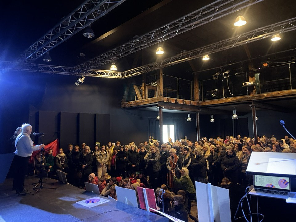 Séð yfir salinn af sviðinu í Edinborgarsal. Á sviðinu standa Kaja og Bryndís, salurinn er fullur af konum.