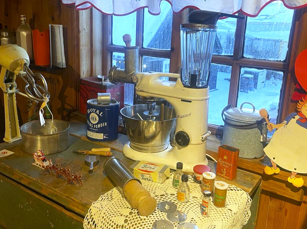 Uppstilling á jólasýningu Byggðasafns Vestfjarða. Hrærivél og matvinnsluvél á borði, bökunardót við hliðina.