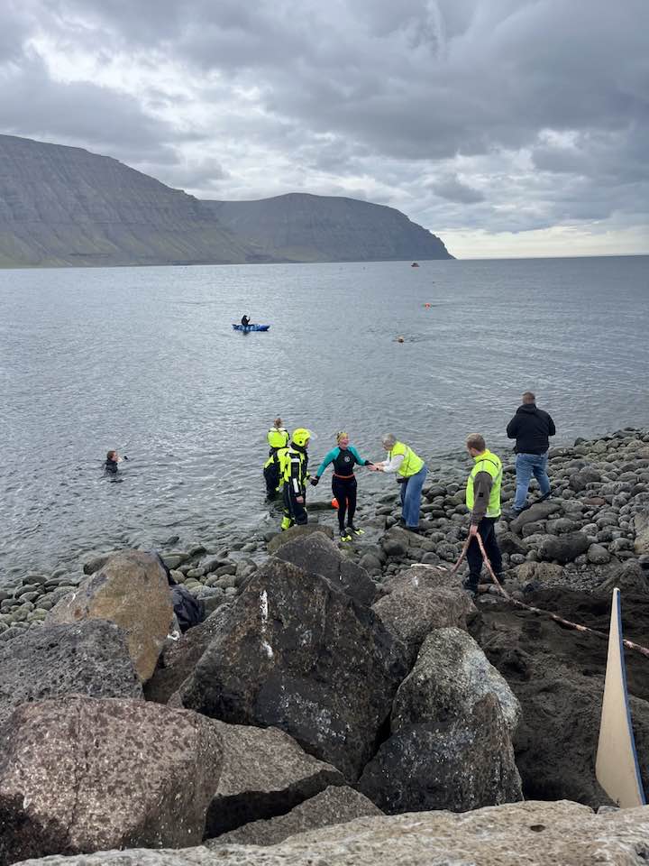 Sjálfboðaliðar aðstoða þátttakendur sem eru að koma í land.