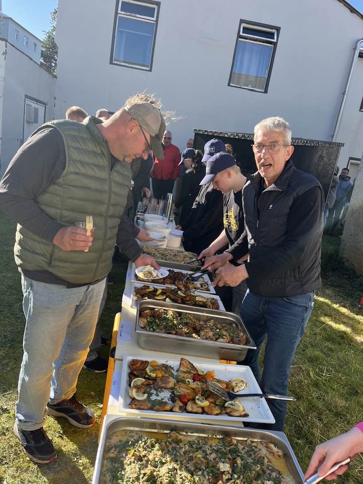 Óðinn Gestsson skenkir fiski af hlaðborði í garðveislu á Suðureyri.