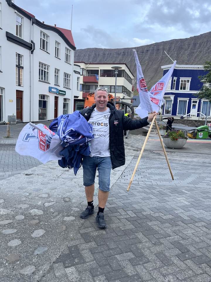 Sjálfboðaliði gengur frá fánum og öðru dóti á torginu að hátíð lokinni.