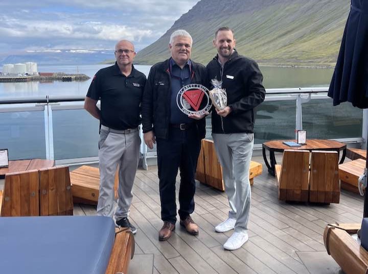 Stýrimaður og skipstjóri Scarlet Lady standa hvor sínum megin við Hilmar hafnarstjóra í skuti skipsins.