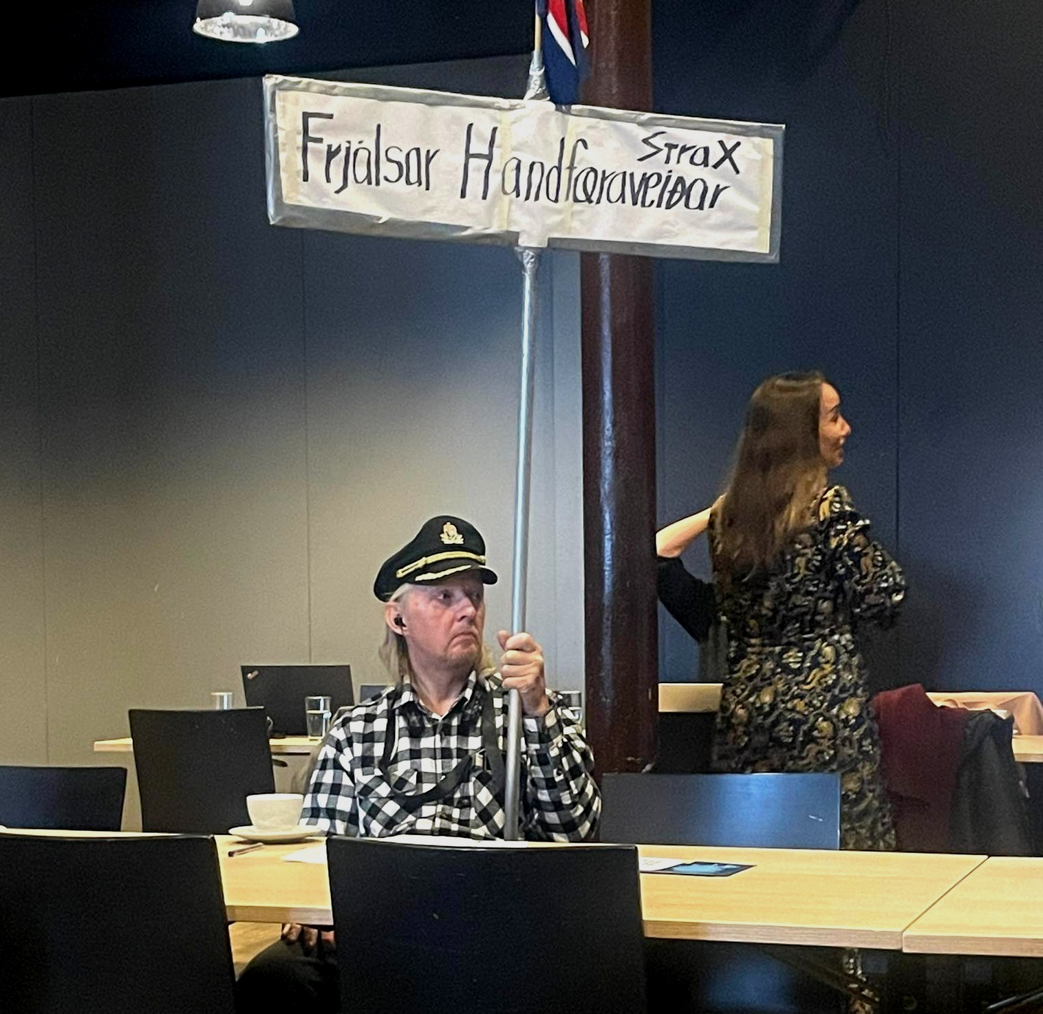 Maður á fundi SFS. Hann er með skipstjórahúfu og heldur á skilti sem á stendur Frjálsar handfæraveiðar strax.