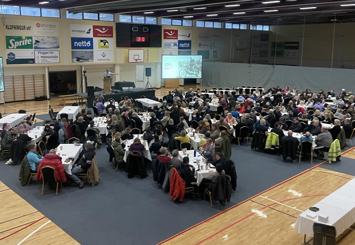Stóri salurinn í íþróttahúsinu á Torfnesi. Starfsfólk Ísafjarðarbæjar situr við mörg langborð. Fyrirlesari stendur uppi á sviði.