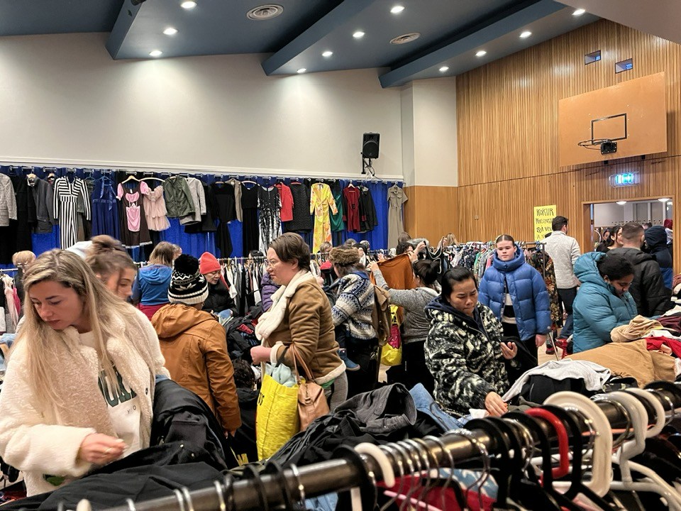 Séð yfir stóra salinn í félagsheimilinu í Hnífsdal. Þar eru lengjur af borðum, fullar af fötum. Fjöldi fólks að skoða úrvalið.