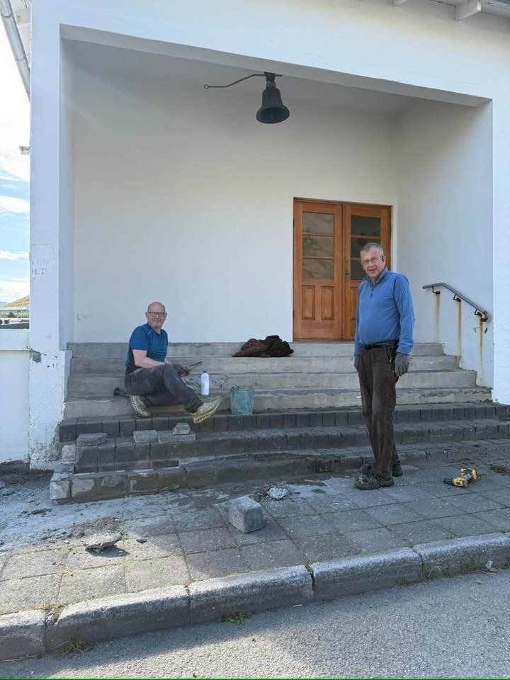 Tveir menn gera við tröppurnar við gamla barnaskólann í Hnífsdal.